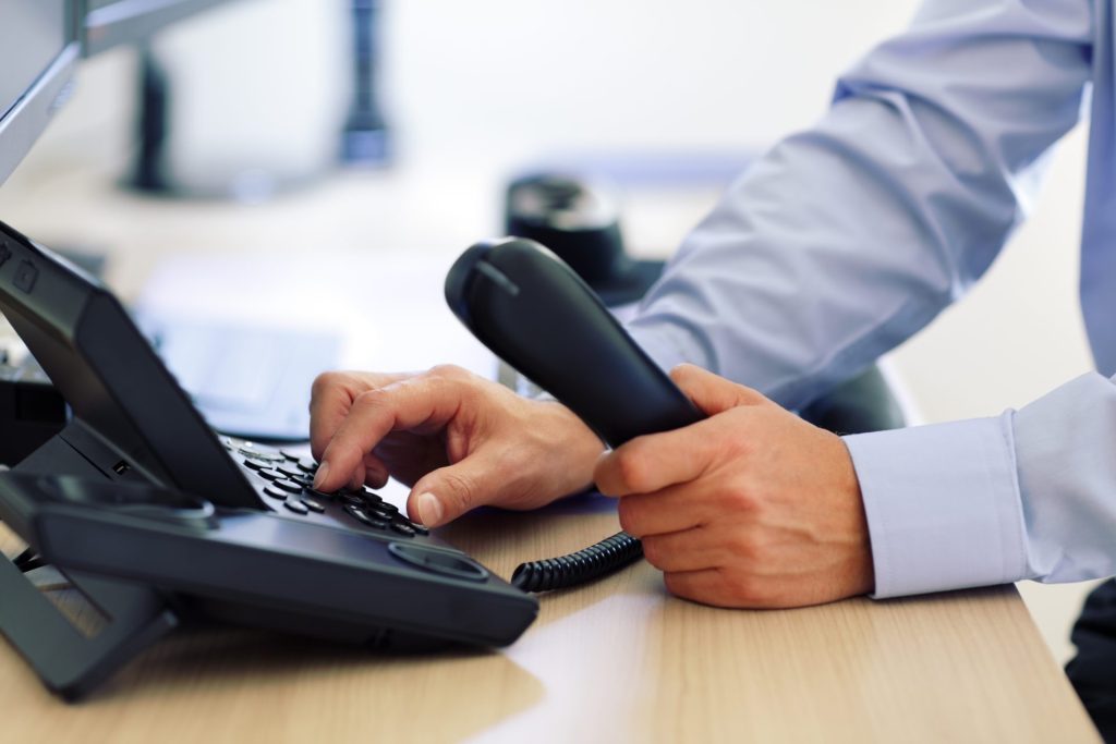 A business man dialing an office phone at a desk