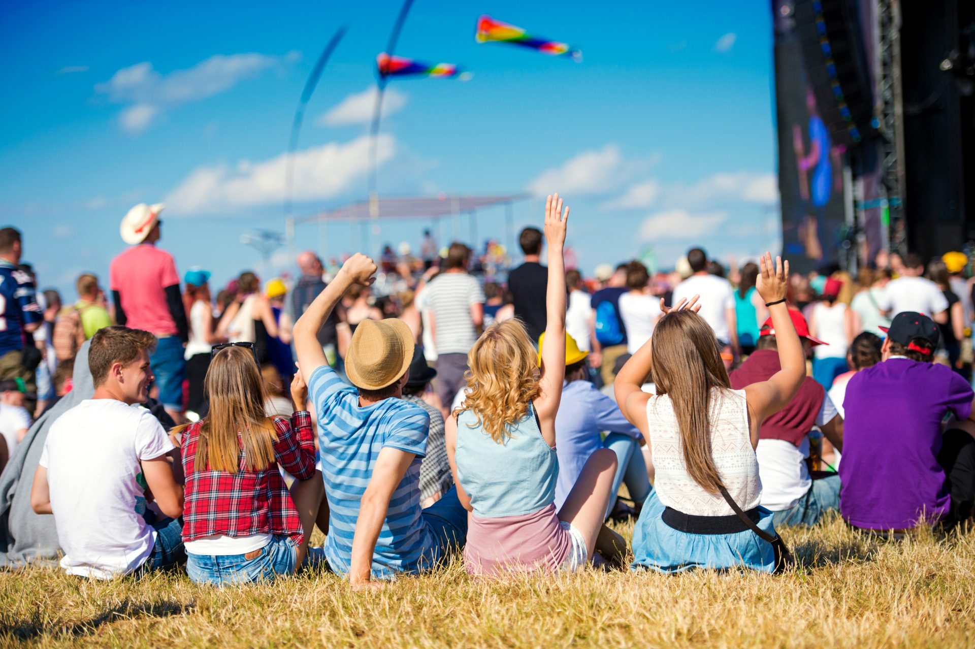 Concert-goers sitting on the ground and watching the stage