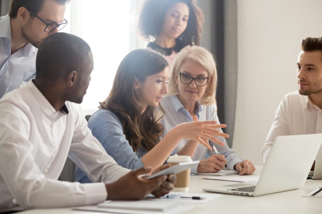 Business men and women huddled around a computer at a desk