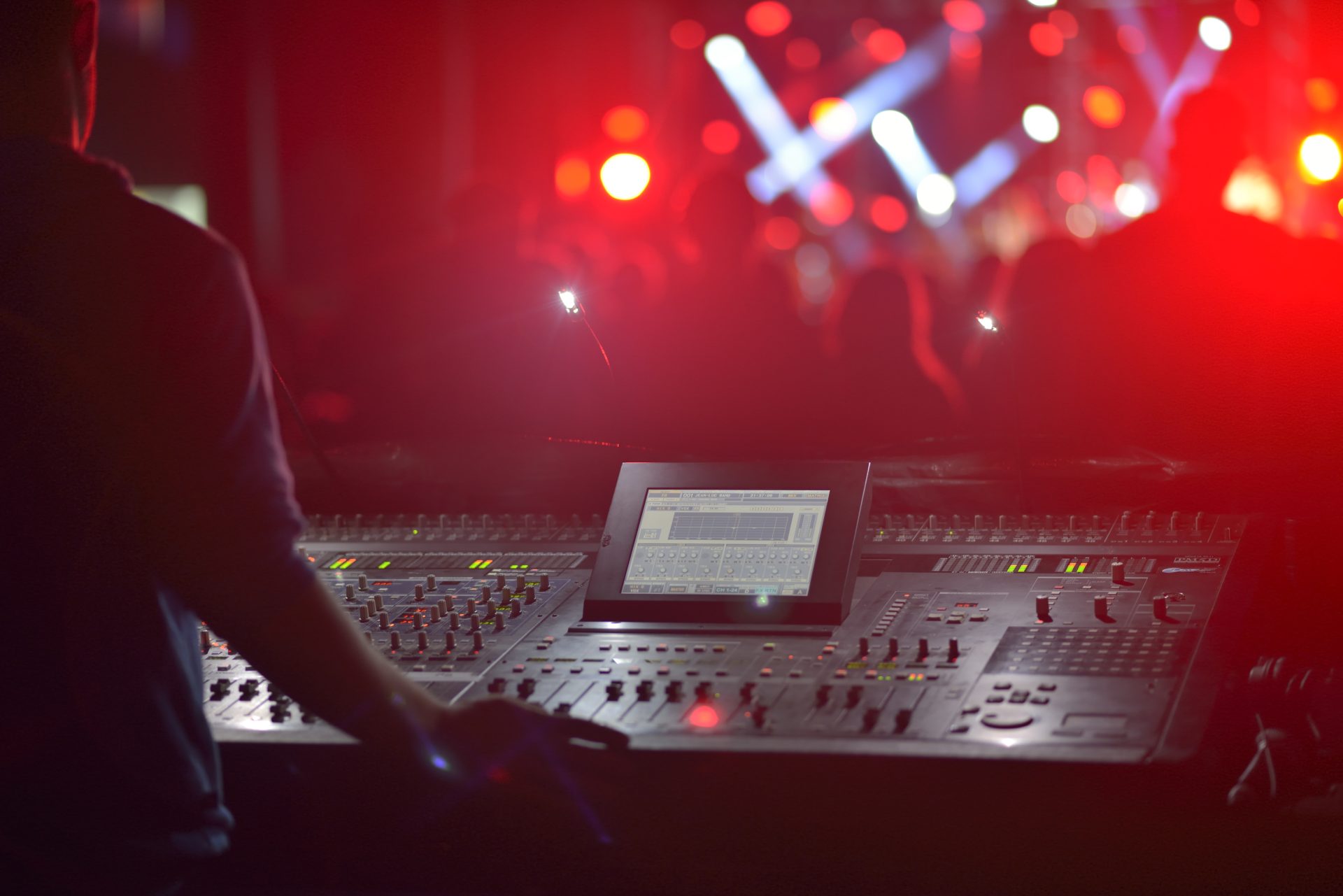 A DJ behind a soundboard at a concert